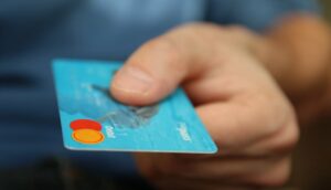 Close-up of a hand holding a blue debit card with a chip visible