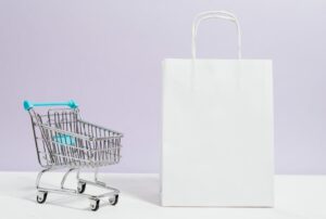 Empty shopping cart next to a plain white shopping bag on a purple background