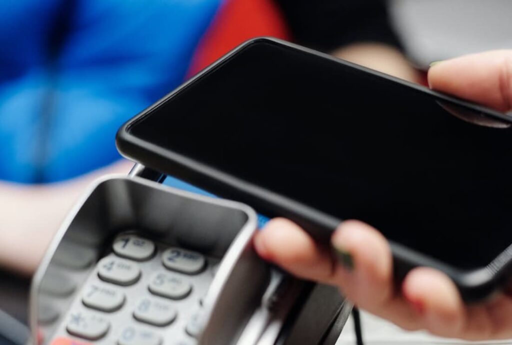 A smartphone being held above a card payment terminal