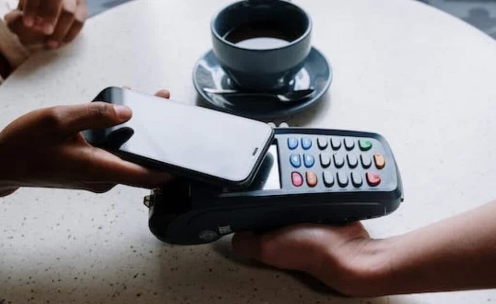 a smartphone is near a payment terminal held by another person