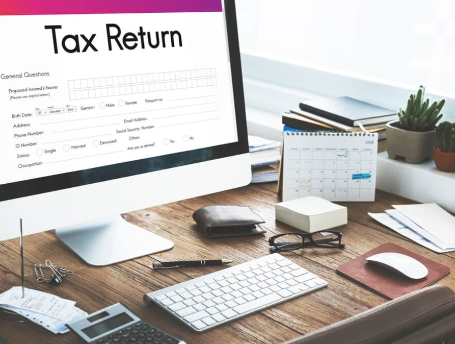 Desktop screen displaying a tax return form with office supplies around