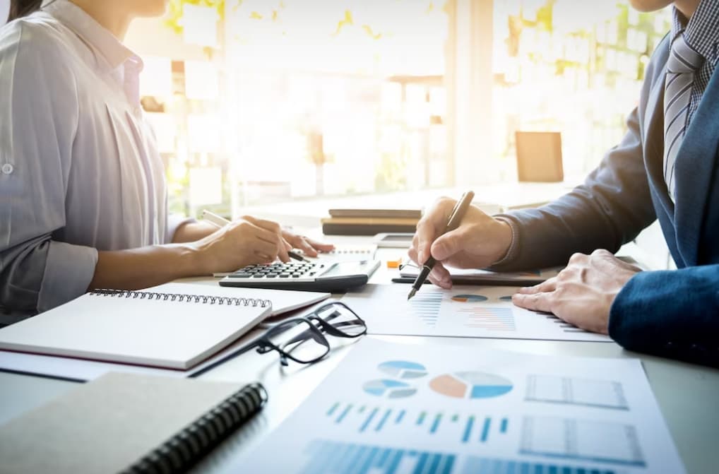 Two professionals analyzing financial charts with calculators