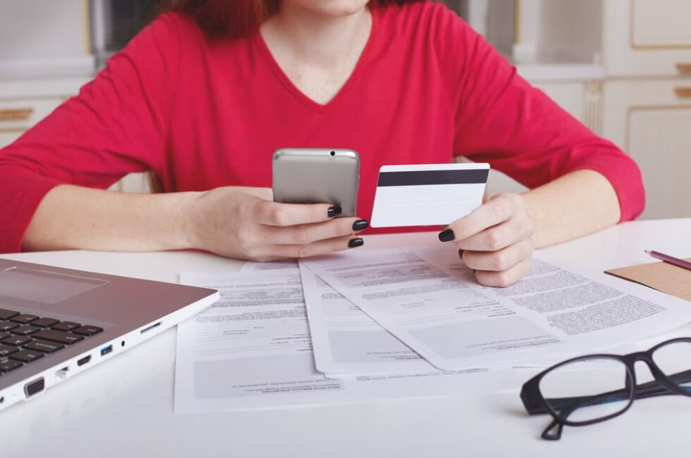 A person online shopping with a phone and credit card