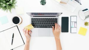 hands near laptop with credit card on table