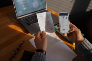 Man comparing a paper bill with a mobile payment app on his phone