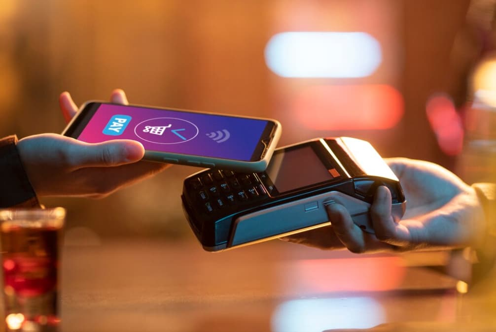 A person using their phone for a contactless payment at a terminal