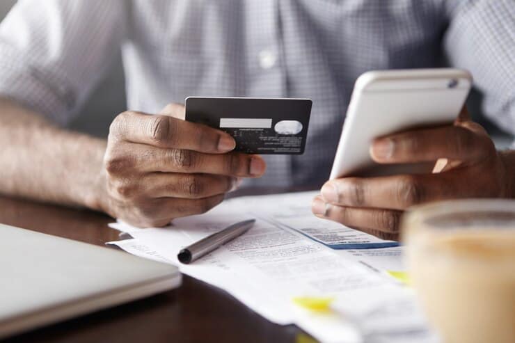 Man Holding Plastic Credit Card and Smartphone